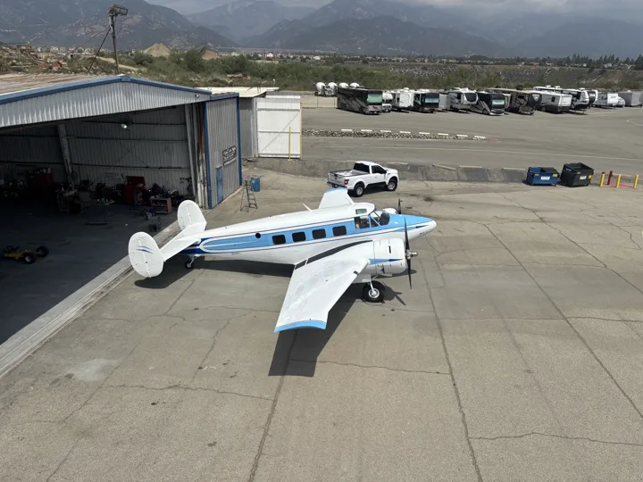Elevated view of a blue and white twin-engine aircraft outside the hangar