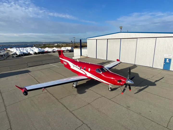 Red and white turboprop aircraft outside a hangar
