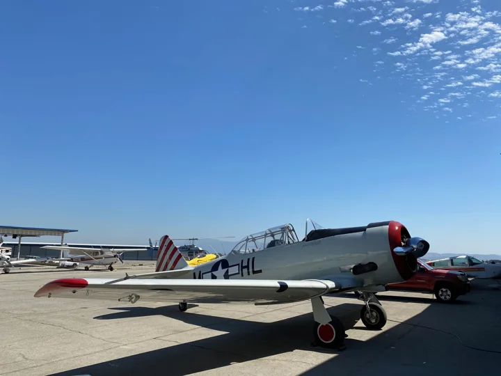 Silver vintage aircraft with a red cowling and tail accents